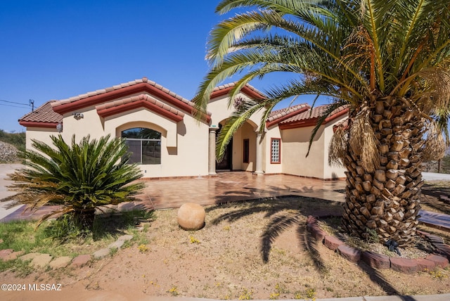 view of front facade featuring a patio area, stucco siding, and a tiled roof