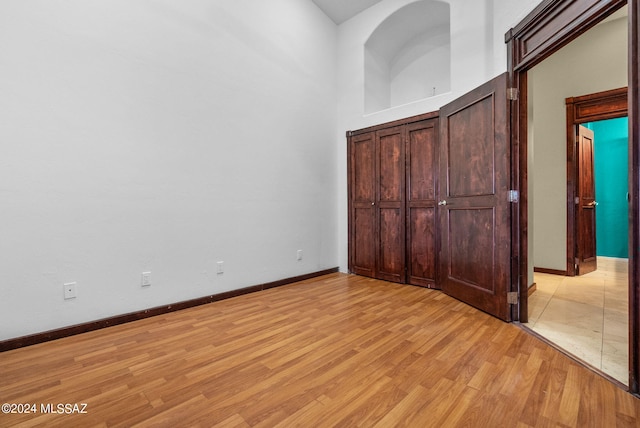 unfurnished bedroom with light hardwood / wood-style floors and a high ceiling