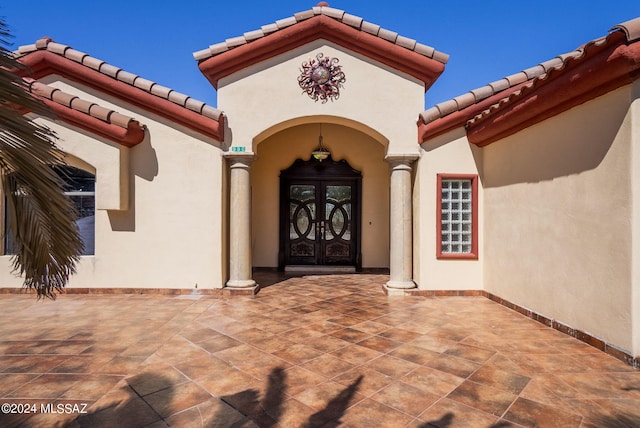property entrance featuring french doors, stucco siding, and a tile roof