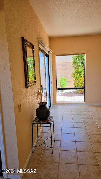 hallway with a textured ceiling and tile patterned floors