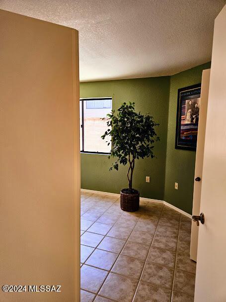 corridor featuring tile patterned floors and a textured ceiling