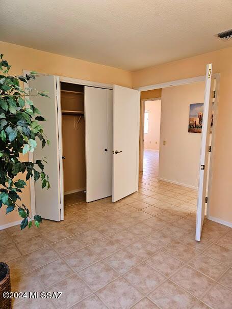 unfurnished bedroom featuring a textured ceiling and a closet