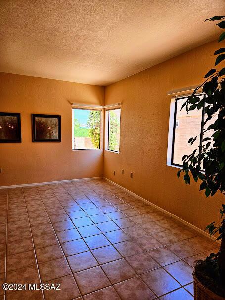 tiled empty room featuring a textured ceiling