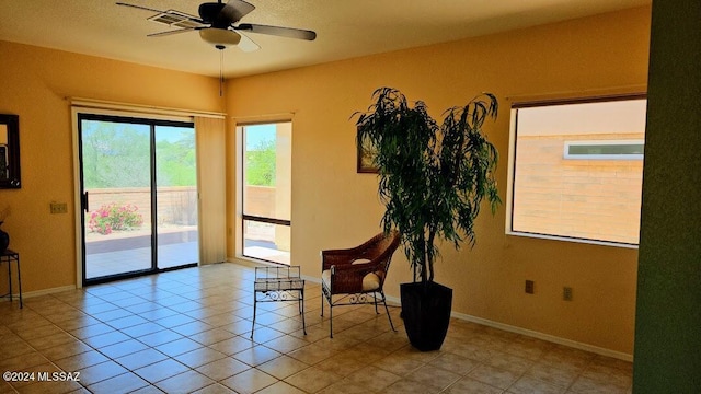 living area with light tile patterned floors and ceiling fan