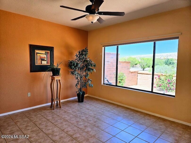 tiled spare room featuring ceiling fan