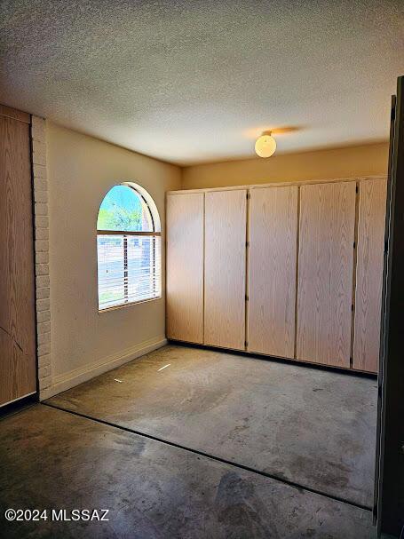 unfurnished bedroom featuring concrete floors and a textured ceiling