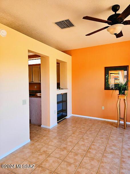 spare room featuring tile patterned floors, ceiling fan, and a textured ceiling