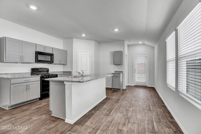 kitchen featuring gray cabinets, black appliances, wood-type flooring, an island with sink, and sink