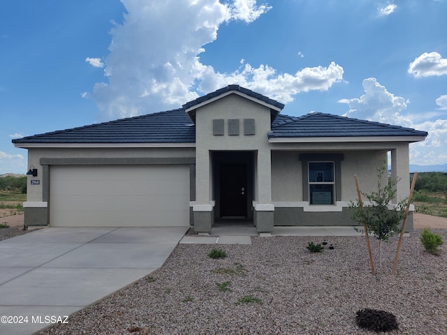 view of front of house with a garage, concrete driveway, stucco siding, and a tile roof