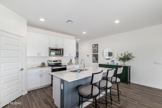 kitchen with visible vents, wood tiled floor, a breakfast bar area, appliances with stainless steel finishes, and a sink