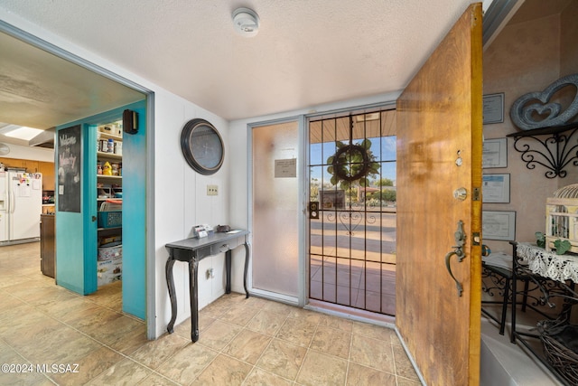 foyer entrance featuring light tile flooring and a textured ceiling