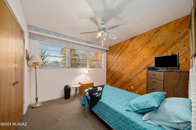 carpeted bedroom with lofted ceiling, a closet, wooden walls, and ceiling fan