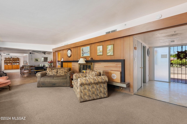 carpeted living room featuring ceiling fan and wood walls