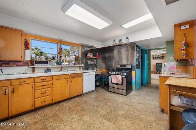 kitchen with tasteful backsplash, white dishwasher, light tile floors, sink, and gas range