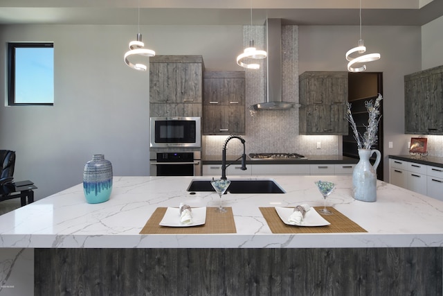 kitchen featuring tasteful backsplash, stainless steel appliances, a kitchen island with sink, and wall chimney exhaust hood