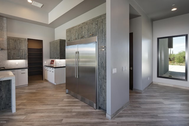 kitchen with stainless steel built in fridge, tasteful backsplash, and light hardwood / wood-style floors