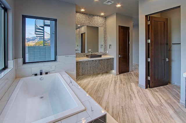 bathroom with a relaxing tiled bath and vanity