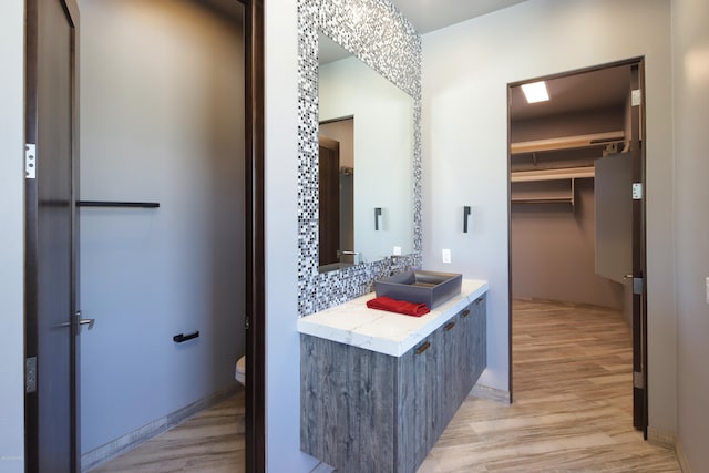 bathroom with toilet, vanity with extensive cabinet space, and hardwood / wood-style flooring