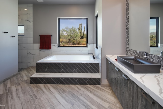 bathroom featuring tiled bath, oversized vanity, and hardwood / wood-style floors