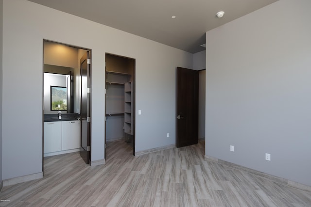 unfurnished bedroom featuring a walk in closet, a closet, and sink