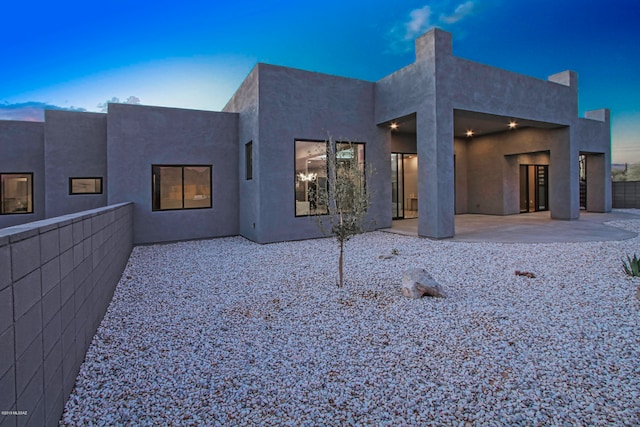 back house at dusk featuring a patio