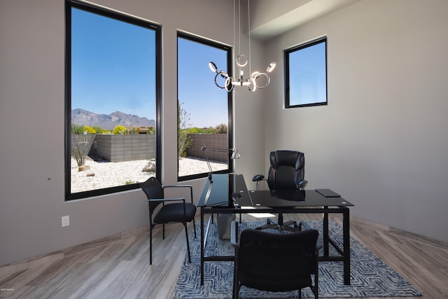 office space with an inviting chandelier, light hardwood / wood-style floors, and a mountain view