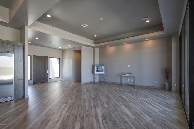 unfurnished living room featuring a raised ceiling and dark wood-type flooring