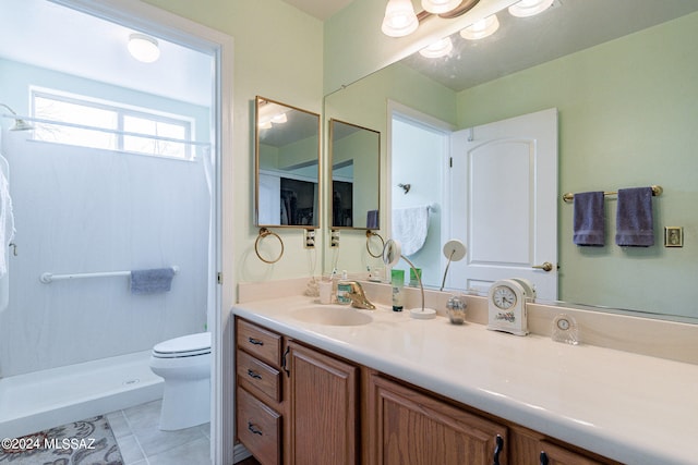 bathroom with vanity, tile flooring, toilet, and walk in shower