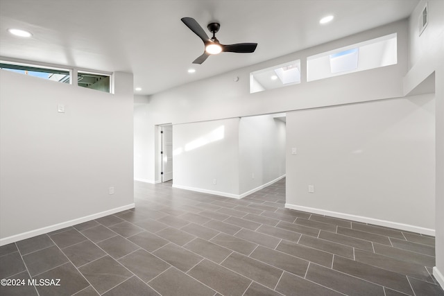 unfurnished room with dark tile patterned flooring, ceiling fan, and a towering ceiling