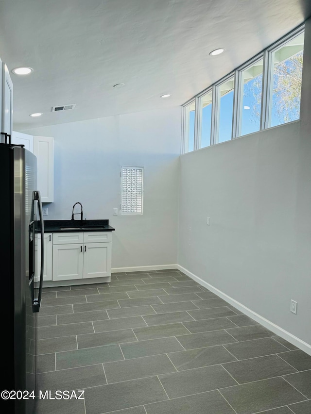 interior space with white cabinets, tile patterned flooring, and stainless steel fridge