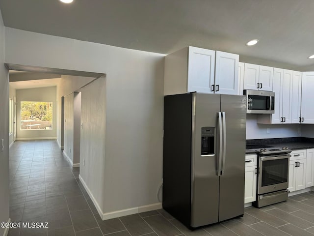 kitchen featuring white cabinets, dark tile patterned flooring, and stainless steel appliances