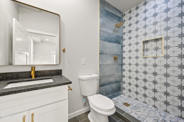 bathroom featuring tile patterned flooring, toilet, vanity, and tiled shower