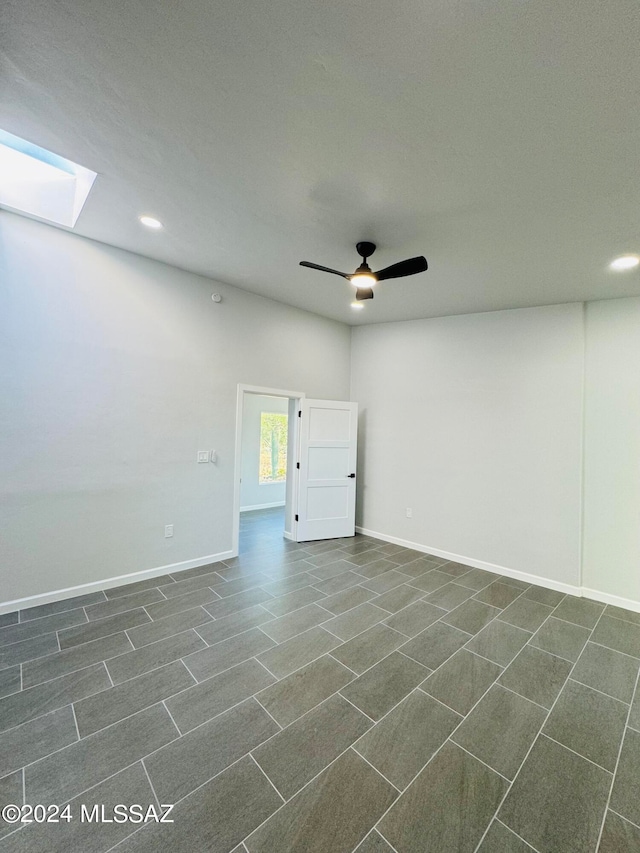 tiled empty room featuring a skylight, a textured ceiling, and ceiling fan