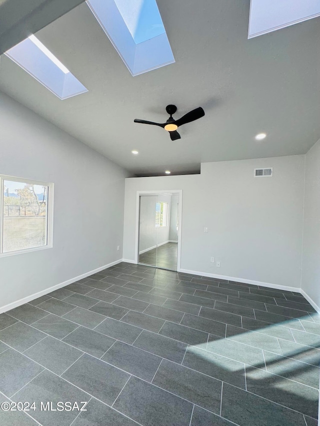 tiled spare room with vaulted ceiling with skylight and ceiling fan