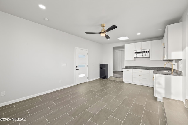 kitchen featuring white cabinets, dark tile patterned floors, sink, and ceiling fan