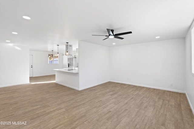 unfurnished living room with recessed lighting, light wood finished floors, and ceiling fan with notable chandelier