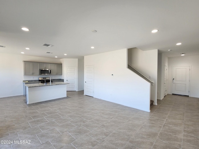 kitchen with dark stone countertops, gray cabinetry, sink, and light tile floors