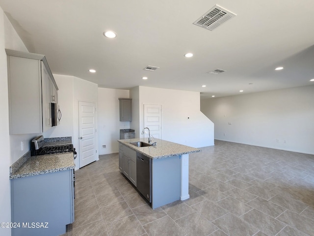 kitchen featuring dishwashing machine, light stone countertops, gray cabinetry, sink, and an island with sink