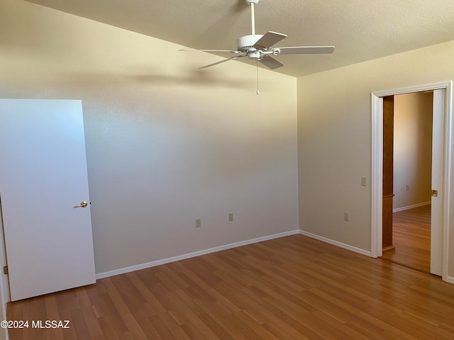 empty room with a textured ceiling, ceiling fan, and wood-type flooring