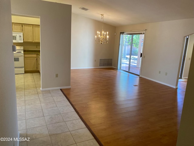 spare room with lofted ceiling, an inviting chandelier, and light hardwood / wood-style floors