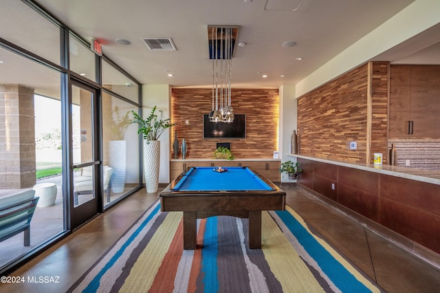 recreation room featuring pool table, wooden walls, concrete flooring, and expansive windows