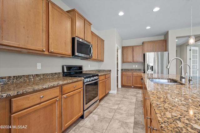 kitchen with light tile patterned flooring, sink, hanging light fixtures, light stone counters, and stainless steel appliances