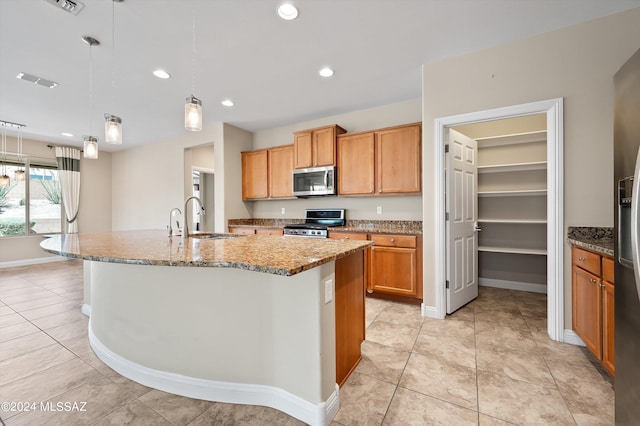 kitchen with hanging light fixtures, an island with sink, appliances with stainless steel finishes, and sink