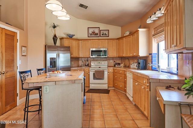 kitchen featuring appliances with stainless steel finishes, tasteful backsplash, a center island, and light tile floors