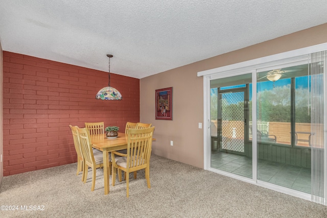 dining area with brick wall, carpet flooring, and a textured ceiling