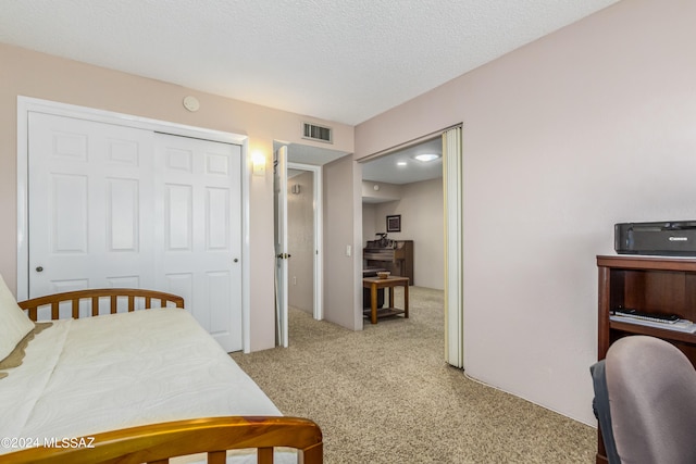 bedroom featuring a textured ceiling, a closet, and light carpet