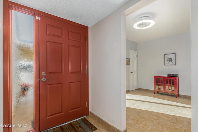 entryway with a textured ceiling and light tile patterned floors