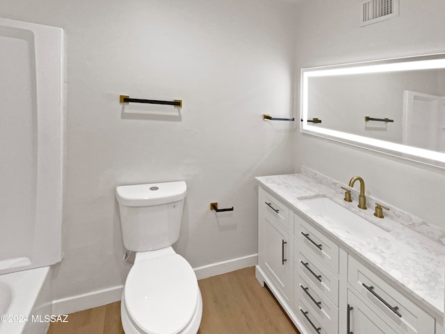 bathroom with vanity, wood-type flooring, toilet, and a washtub