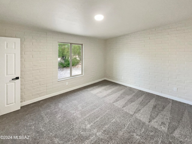 spare room featuring brick wall, carpet flooring, and lofted ceiling