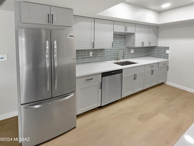 kitchen featuring light hardwood / wood-style floors, stainless steel appliances, decorative backsplash, and sink